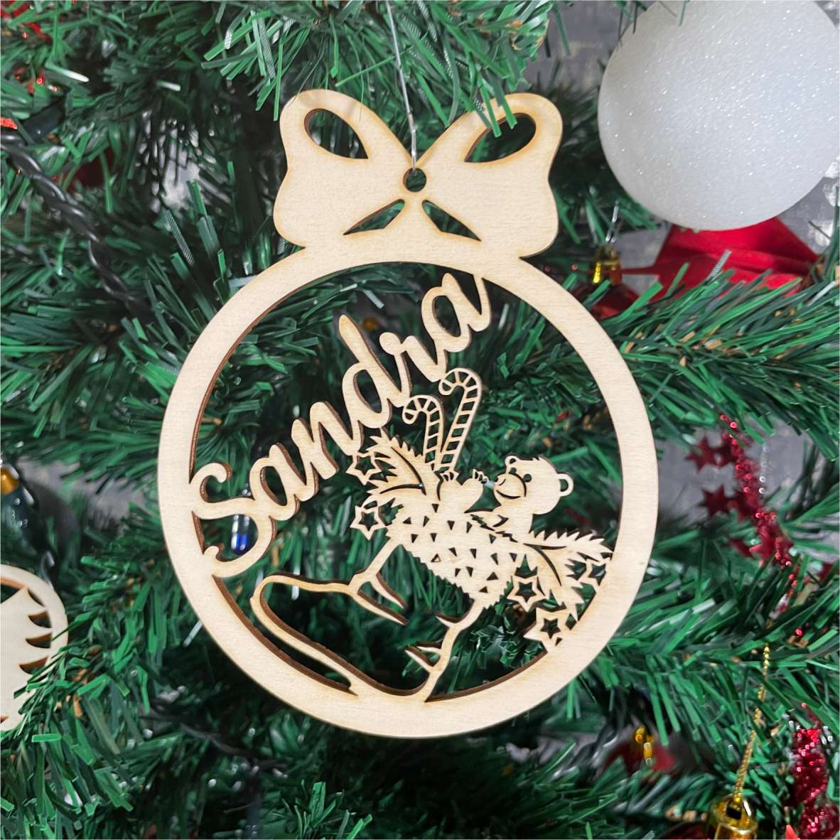 Personalisierte Holz-Weihnachtskugel mit Nikolausstiefel und Name Sandra zwischen Tannenzweigen