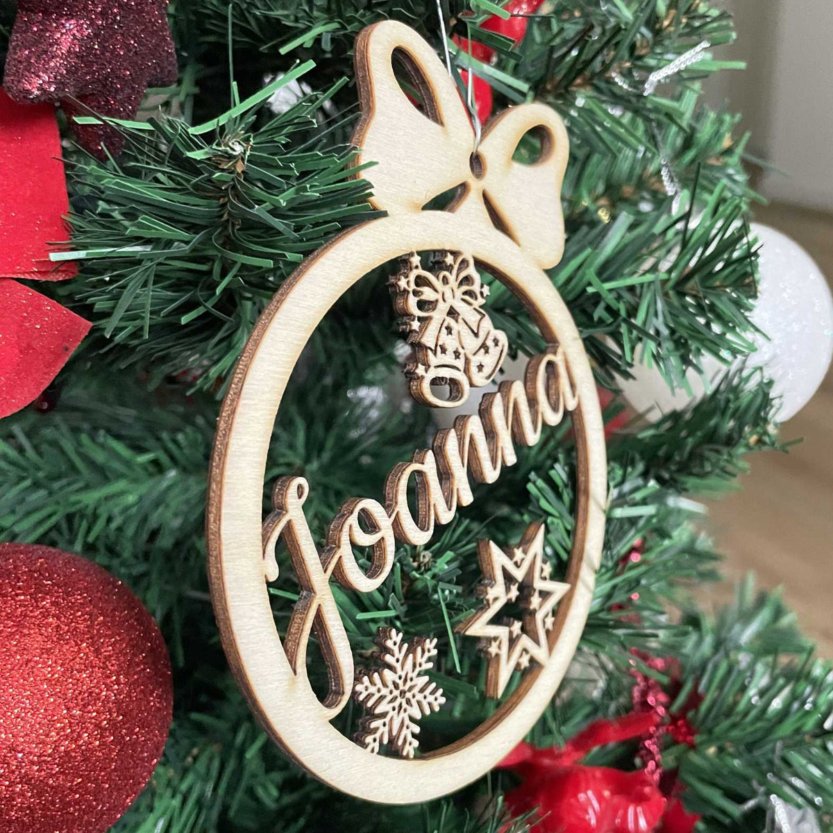 Seitliche Ansicht der personalisierten Holz-Weihnachtskugel „Sternenlicht“ am Tannenzweig