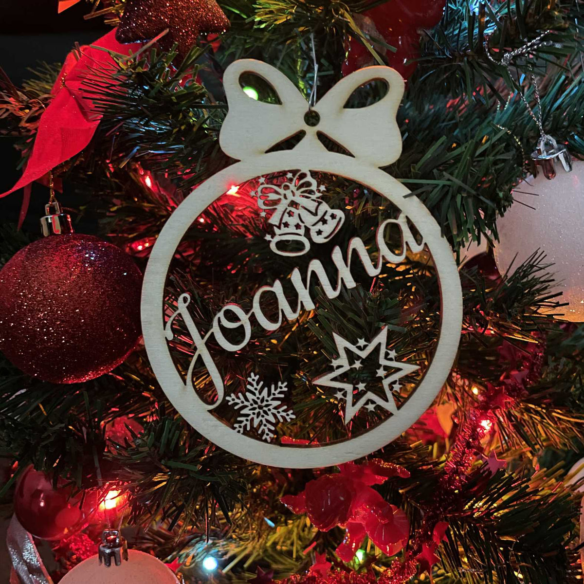 Holz-Weihnachtskugel „Sternenlicht“ mit Name Joanna zwischen roter Weihnachtsdekoration