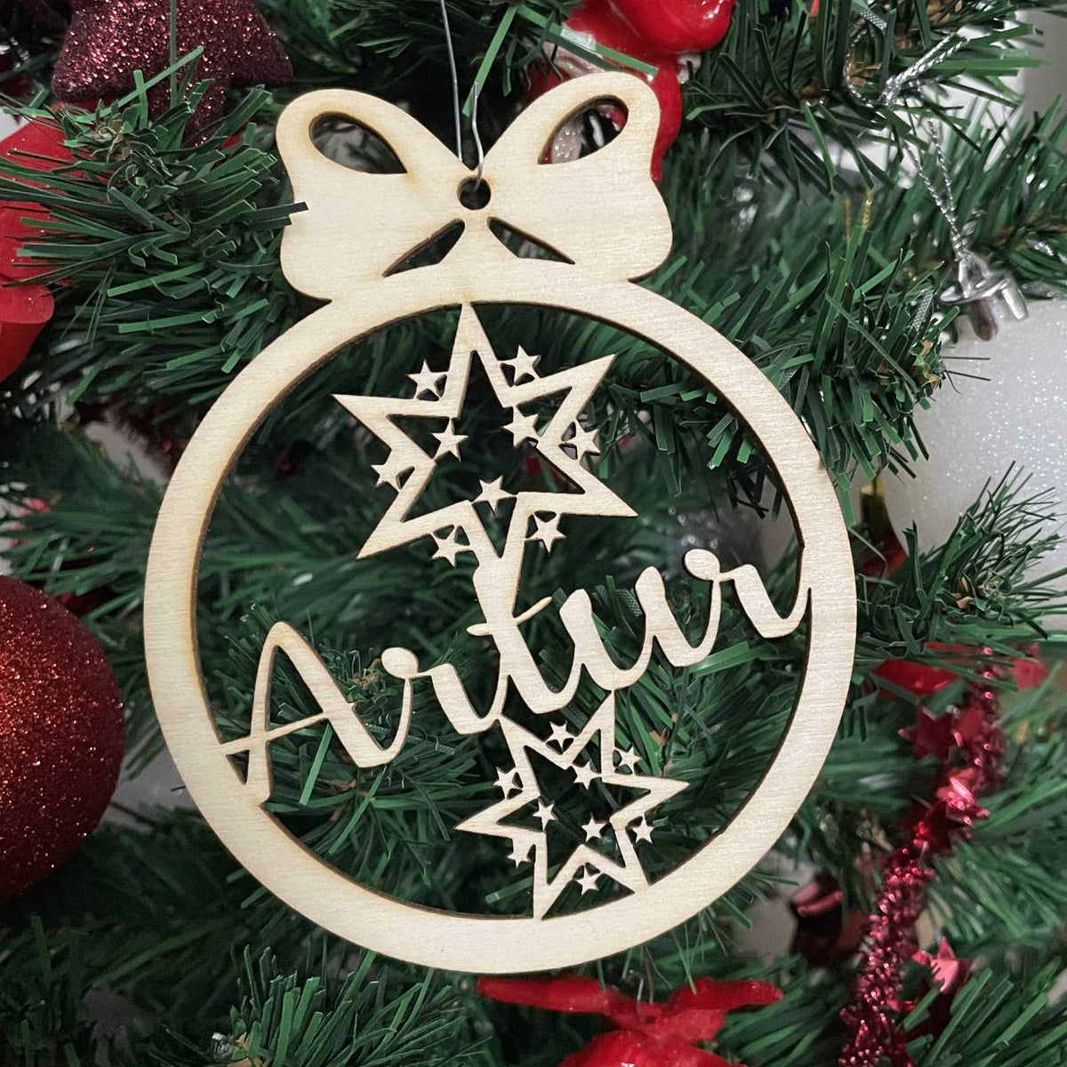 Holz-Weihnachtskugel „Sterne“ mit Name Artur am geschmückten Tannenbaum